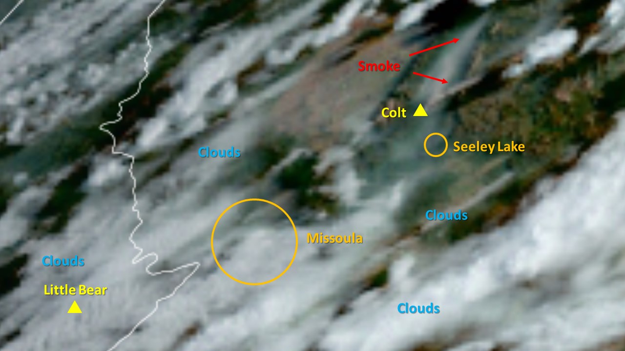 A satellite photo showing smoke from the Colt Fire over the Seeley-Swan valleys and creating a plume heading west. Clouds cover much of the rest of the photo.